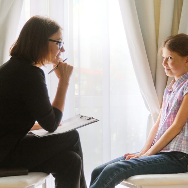 Girl talking to woman counselor psychologist discussing the feelings of child